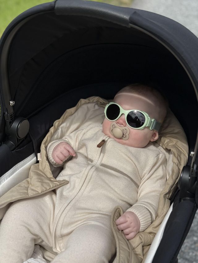 Baby in a stroller wearing Mokki Click & Change sunglasses and a beige outfit