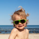 Gutt på stranda med grønne Click & Change-solbriller for barn