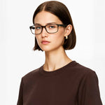 Woman wearing black Mokki glasses and a brown shirt on a white background