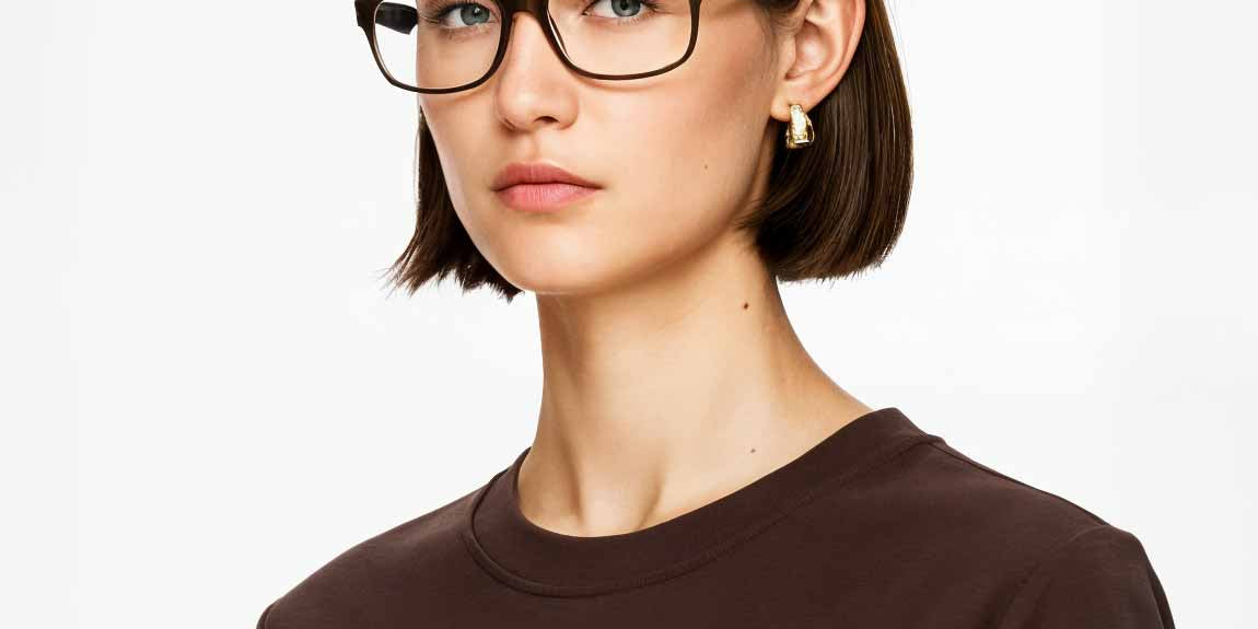Woman wearing black Mokki glasses and a brown shirt on a white background