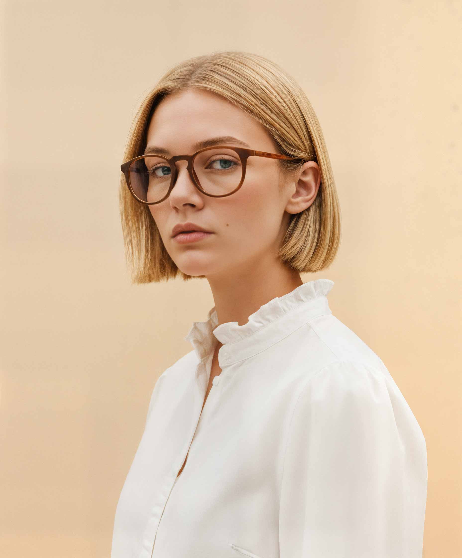 Woman wearing Mokki reading glasses and a white shirt against a beige background