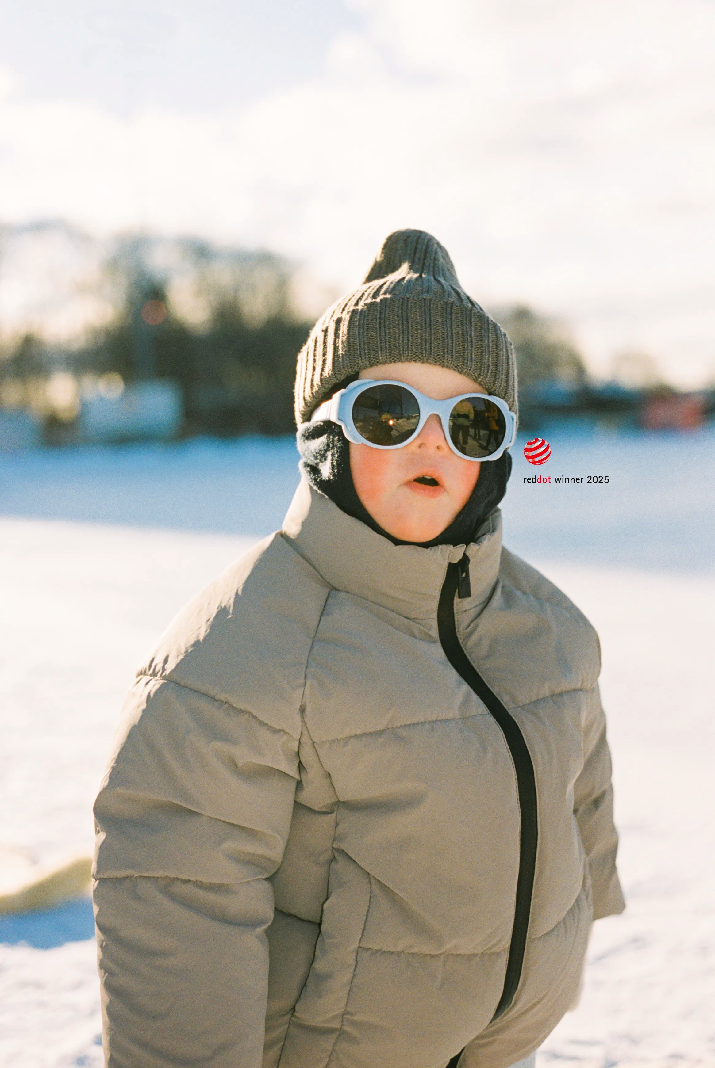 Boy wearing a winter coat, beanie, and the award-winning Click & Change sunglasses in a snowy landscape.