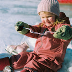 Child in winter clothing sitting on ice, showing how ultra-flexible the Mokki Click & Change sunglasses are