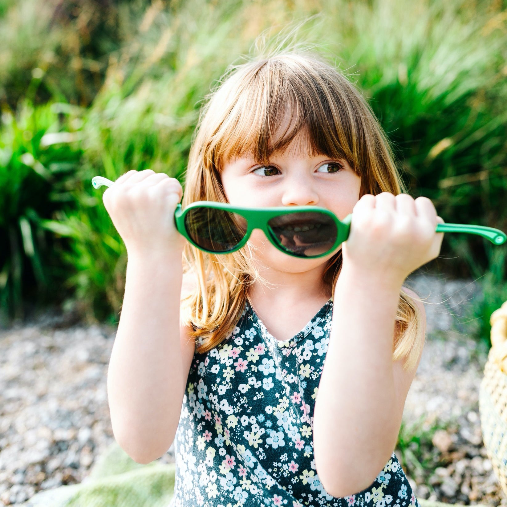 A girl is bending a pair of Click & Change sunglasses for kids 