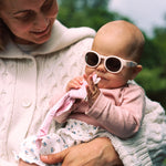 Woman holding a baby wearing Mokki Click & Change sunglasses outdoors