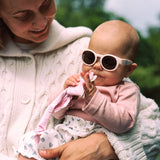 Woman holding a baby wearing Mokki Click & Change sunglasses outdoors