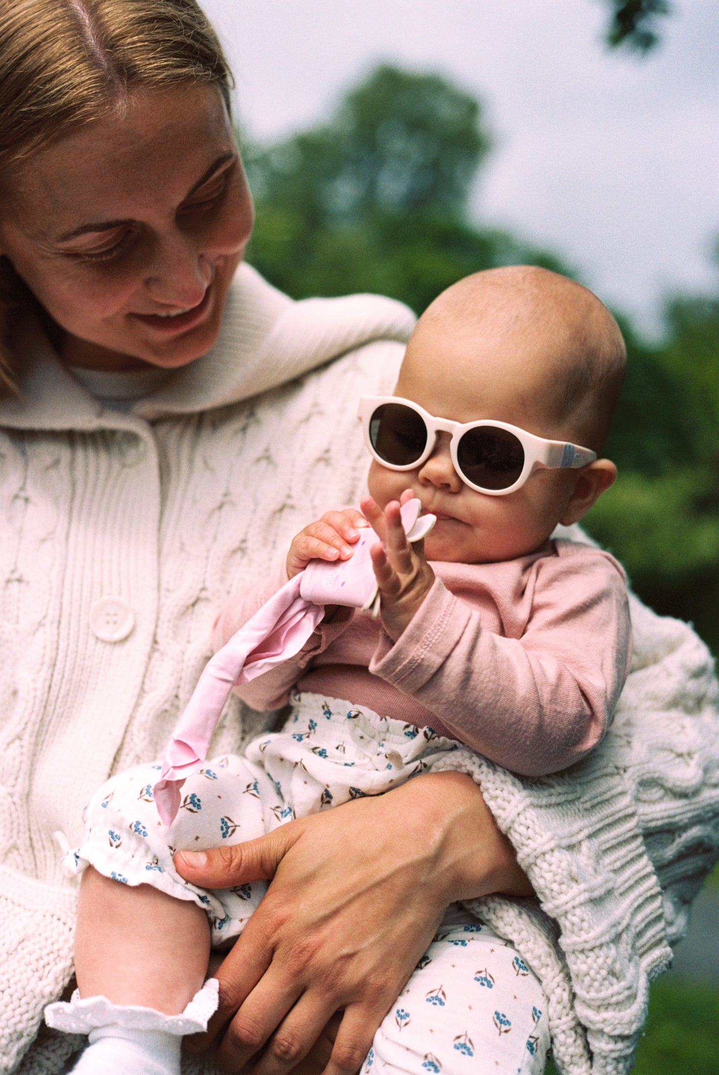 Woman holding a baby wearing Mokki Click & Change sunglasses outdoors