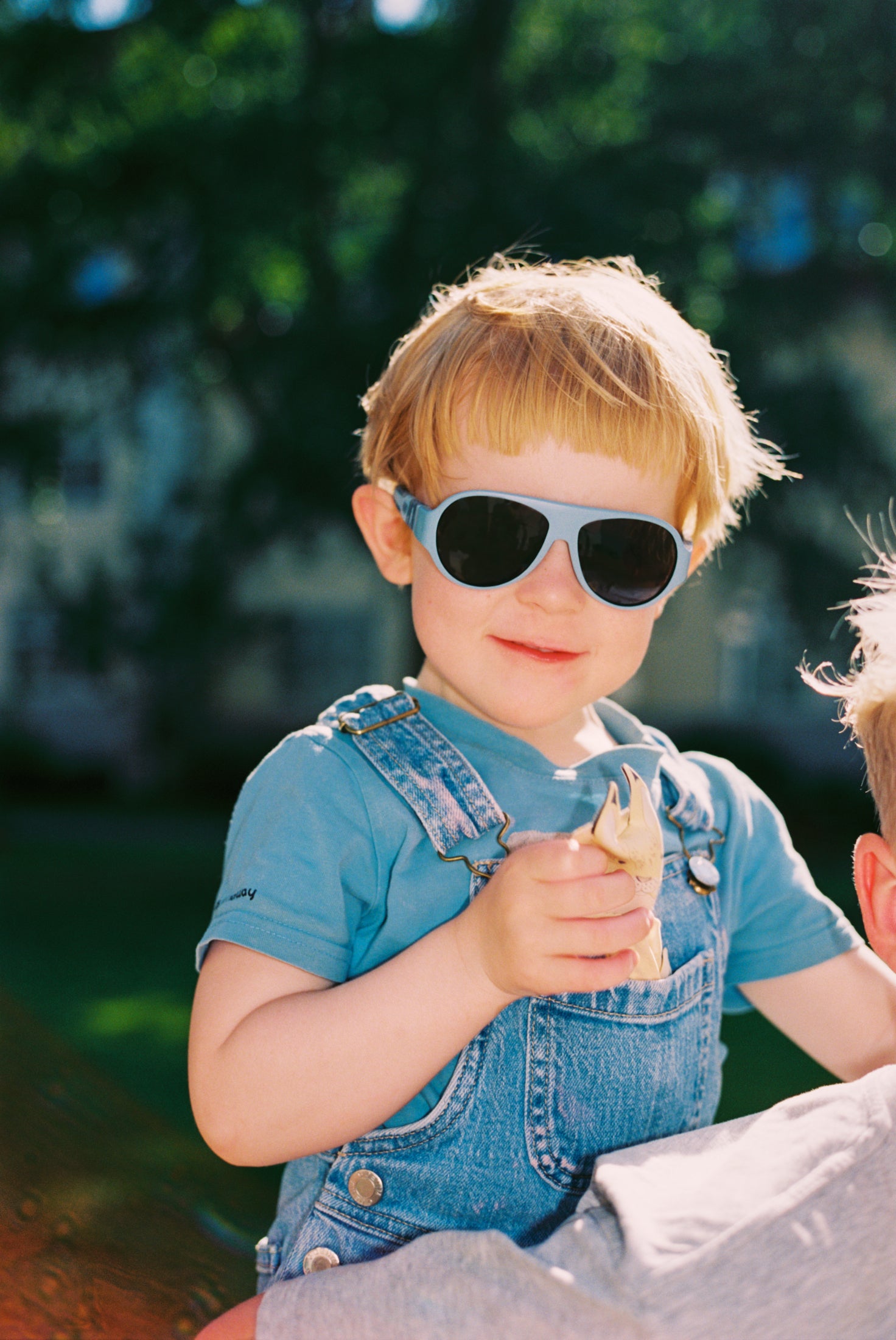 Child wearing Mokki Click & Change sunglasses and a denim outfit outdoors