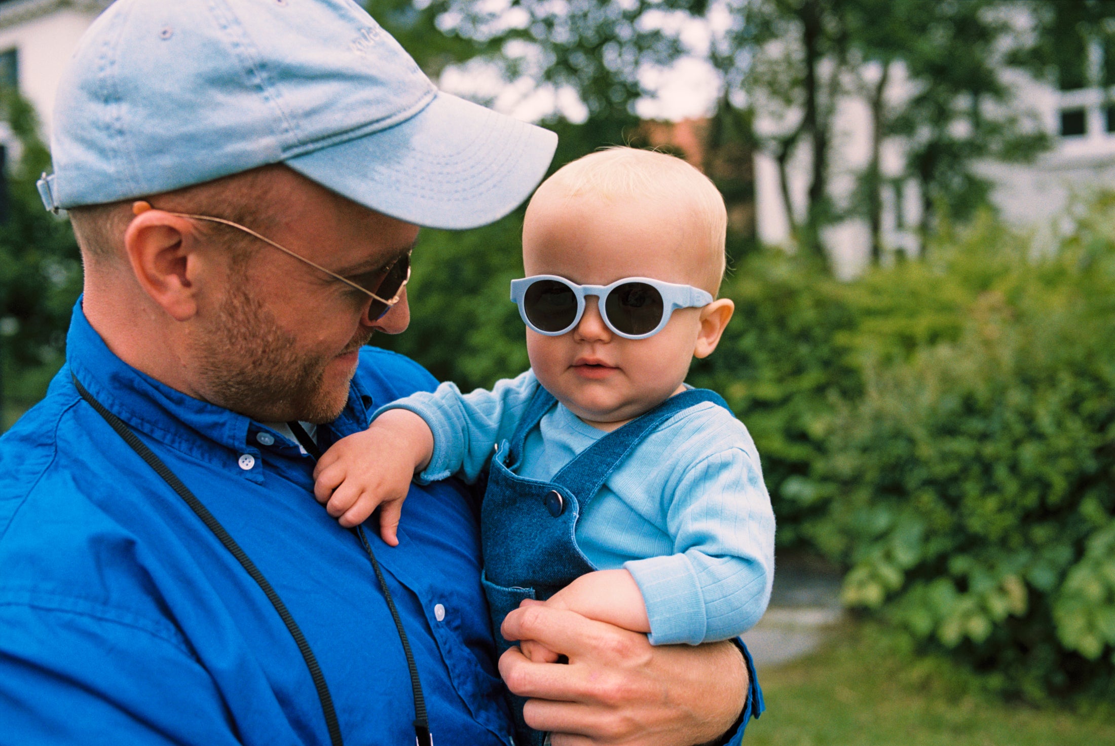 Father holding his baby outdoors, both wearing Mokki sunglasses.