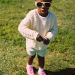 Young girl wearing Mokki Click & Change sunglasses and a white sweater on grass