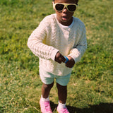 Young girl wearing Mokki Click & Change sunglasses and a white sweater on grass