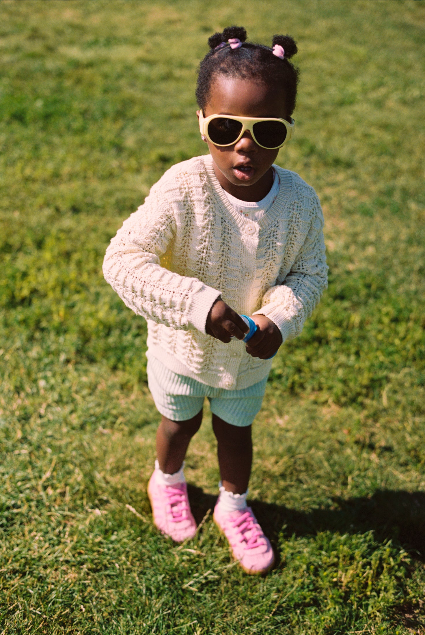 Young girl wearing Mokki Click & Change sunglasses and a white sweater on grass