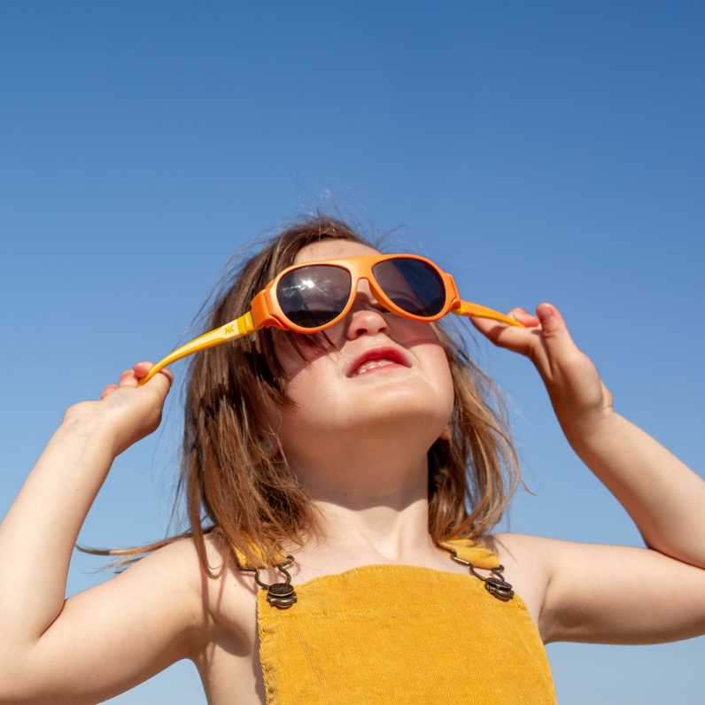 A girl wearing Click & Change sunglasses for kids in yellow