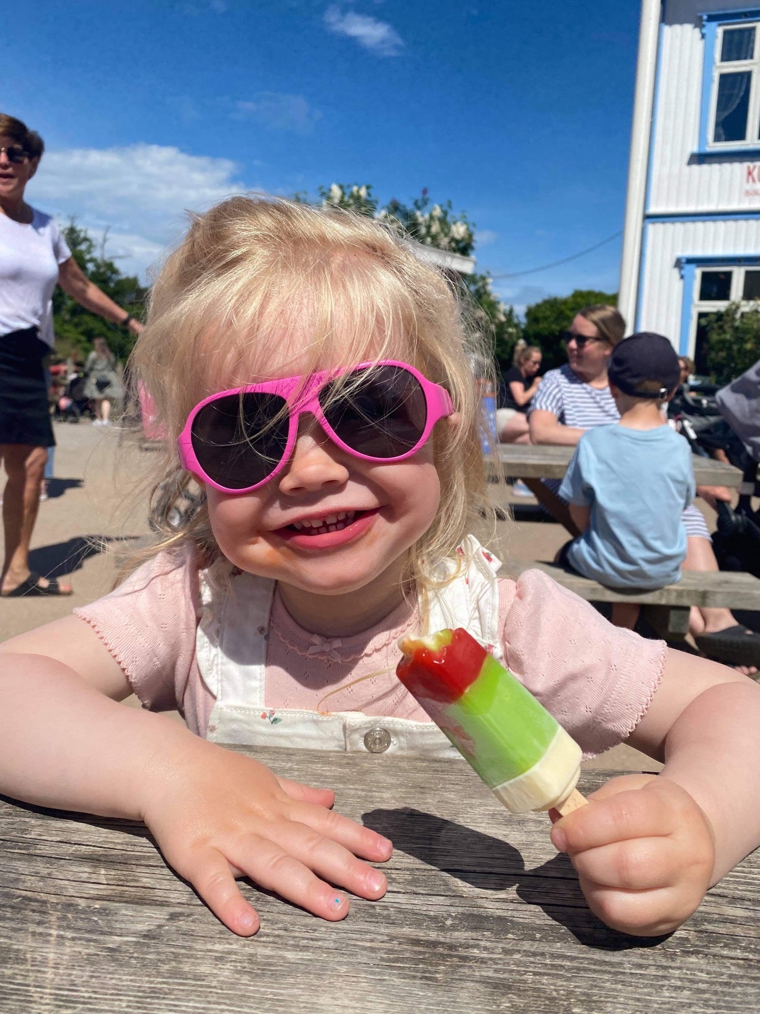 A young girl enjoying her ice cream in the sun wearing sunglasses from Mokki