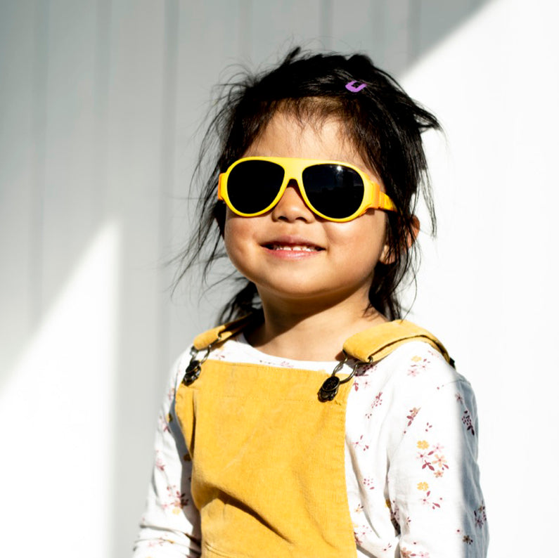 A girl wearing yellow Click & Change sunglasses for kids 