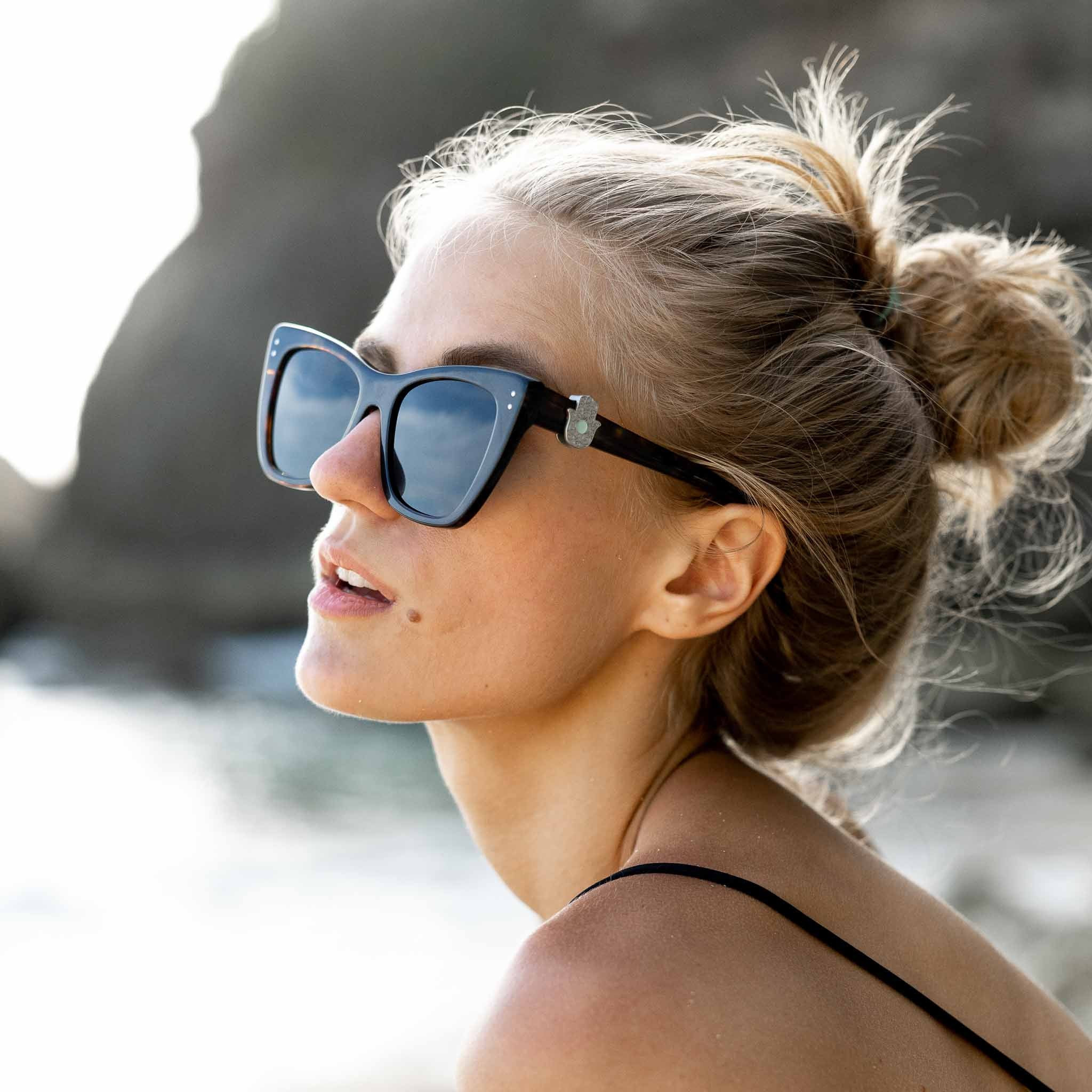 Woman wearing Mokki sunglasses with hamsa symbol